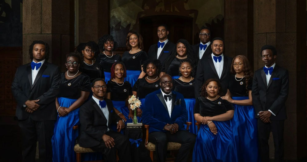 The Fisk Jubilee Singers, a group of young Black and African American vocal artists, pose wearing shades of royal blue and black.